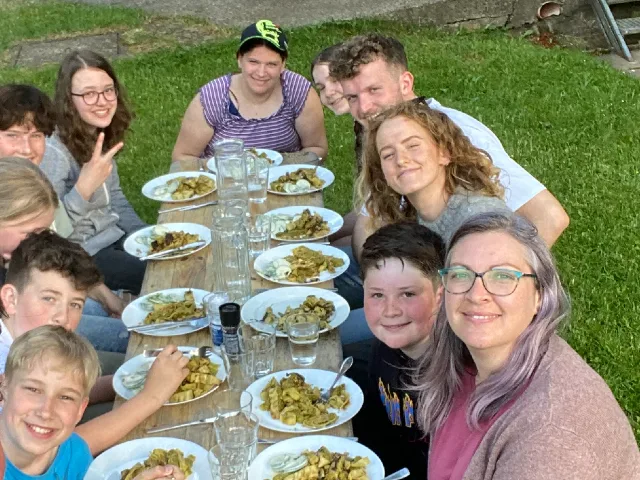 Geschwister-Kinder sitzen im Garten und essen gemeinsam