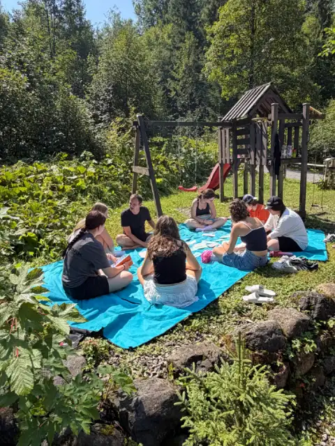 Gruppe sitzt auf einer Decke im Freien